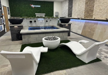 Showroom Lounge chairs and firepit facing a water feature in the Gorman Baymeadoes pool showroom