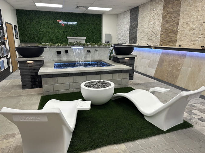 Lounge chairs and firepit in fron of a waterfall in the Gorman Bay Meadows pool showroom